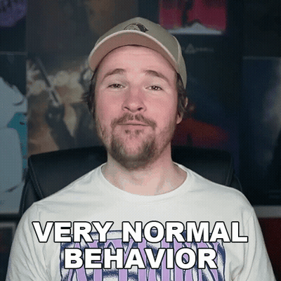 A Man With A Beard Wearing A White Shirt That Says Very Normal Behavior GIF