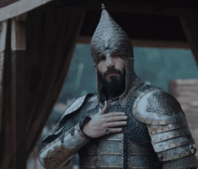 A Man With A Beard Wearing Armor And A Helmet With His Hand On His Chest GIF