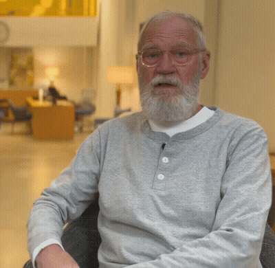 A Man With A Beard Wearing Glasses And A Grey Shirt Gives A Thumbs Up GIF
