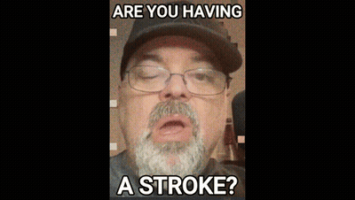 A Man With A Beard Wearing Glasses And A Hat Says Are You Having A Stroke GIF