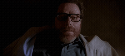 A Man With A Beard Wearing Glasses And A White Coat Is Laying Down In A Dark Room . GIF