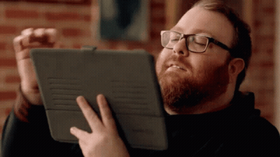 A Man With A Beard Wearing Glasses Is Holding A Tablet GIF