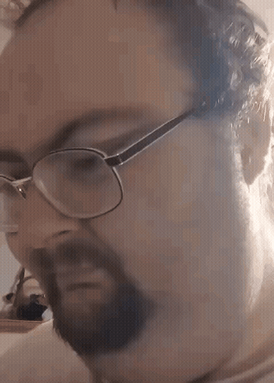 A Man With A Beard Wearing Glasses Is Making A Funny Face . GIF