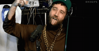 A Man With A Beard Wearing Headphones And A Gold Chain Sticks Out His Tongue GIF