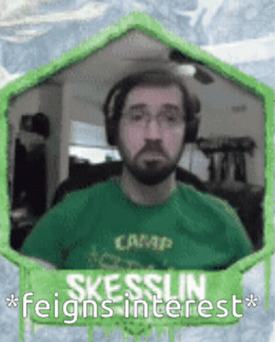 A Man With A Beard Wearing Headphones And A Green Shirt With The Words Skesslin Feigns Interest GIF