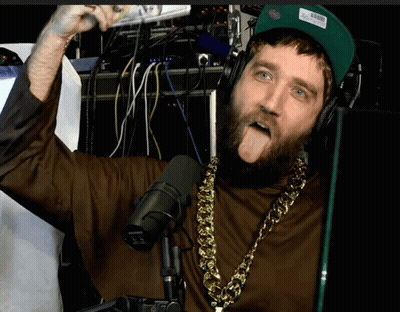 A Man With A Beard Wearing Headphones And A Shure Microphone Sticking Out His Tongue GIF