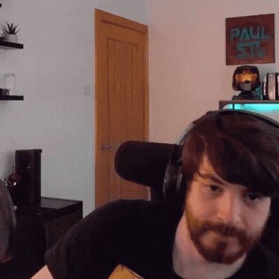 A Man With A Beard Wearing Headphones In Front Of A Paul Stan Poster GIF
