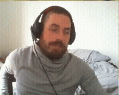 A Man With A Beard Wearing Headphones Is Sitting In Front Of A Computer . GIF