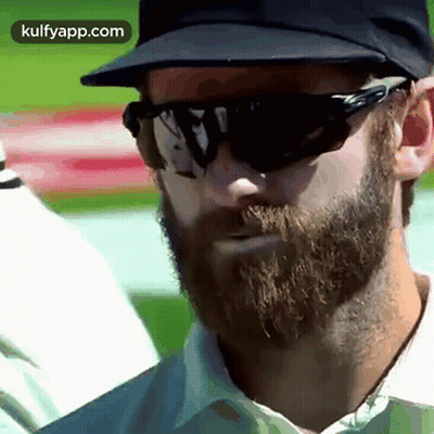 A Man With A Beard Wearing Sunglasses And A Baseball Cap . GIF