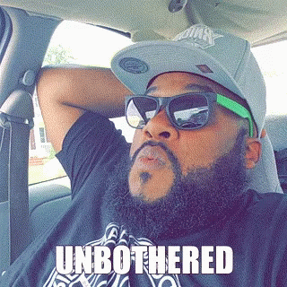 A Man With A Beard Wearing Sunglasses And A Hat Has The Word Unbothered On His Shirt GIF