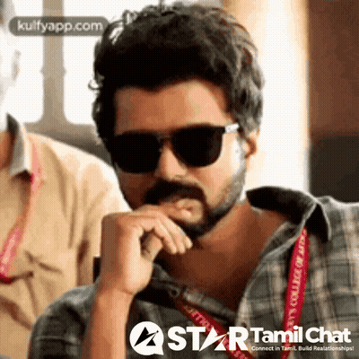 A Man With A Beard Wearing Sunglasses And A Plaid Shirt Is Sitting With His Hand On His Chin . GIF