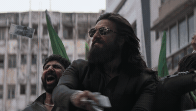 A Man With A Beard Wearing Sunglasses Holds A Piece Of Paper In His Right Hand GIF