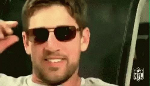 A Man With A Beard Wearing Sunglasses Is Smiling And Making A Funny Face . GIF