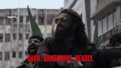 A Man With A Beard Wearing Sunglasses Stands In Front Of A Sign That Says " Dark Dangerous Deadly " On It GIF