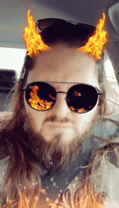A Man With A Beard Wearing Sunglasses With Flames Coming Out Of Them GIF