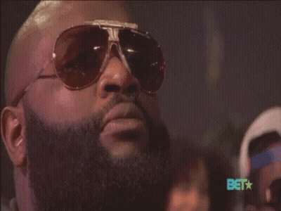 A Man With A Beard Wearing Sunglasses With The Bet Logo In The Background GIF