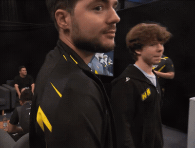 A Man With A Beard Wears A Black And Yellow Jacket That Says Nm GIF