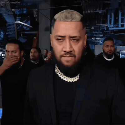 A Man With A Beard Wears A Black Suit And Gold Chain GIF