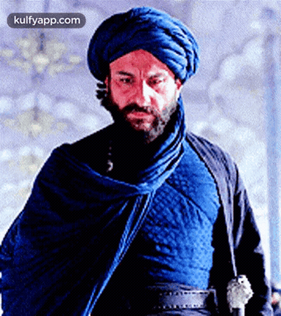 A Man With A Beard Wears A Blue Turban And A Blue Cloak GIF