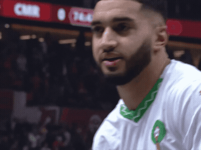A Man With A Beard Wears A White Shirt With A Green Trim GIF