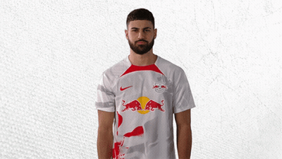 A Man With A Beard Wears A White Shirt With A Red Bull On It GIF