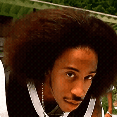A Man With A Big Afro And A Mustache Is Wearing A Black And White Jersey . GIF