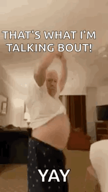 A Man With A Big Belly Is Standing In A Living Room With His Arms Up . GIF