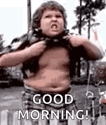 A Man With A Big Belly Is Standing In Front Of A Fence And Saying `` Good Morning '' . GIF