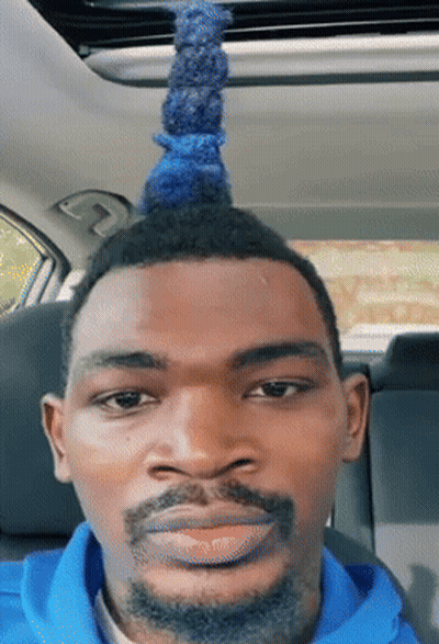 A Man With A Blue Mohawk And A Beard Looks At The Camera GIF