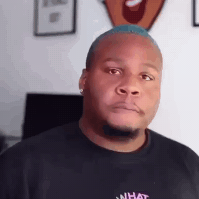 A Man With A Blue Mohawk Is Wearing A Black T-Shirt With The Word What On It . GIF