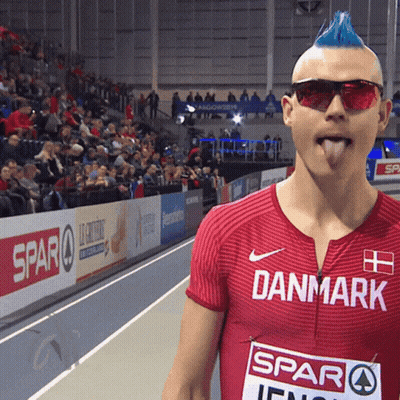 A Man With A Blue Mohawk Wearing Sunglasses And A Red Shirt That Says Danmark GIF