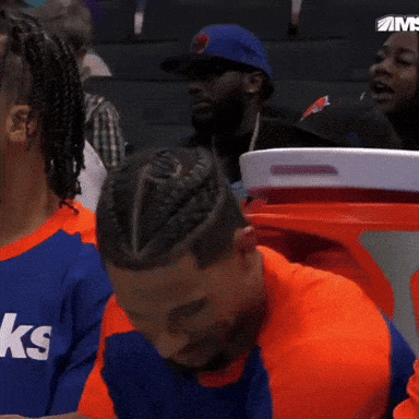 A Man With A Braided Hairdo Is Sitting In A Stadium Watching A Game GIF
