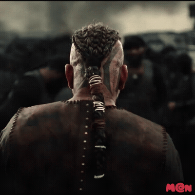 A Man With A Braided Ponytail And A Tattoo On His Face Is Standing In Front Of A Crowd GIF