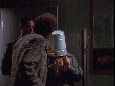 A Man With A Bucket On His Head Is Talking To Another Man With The Words Tell The World My Story Below Him GIF