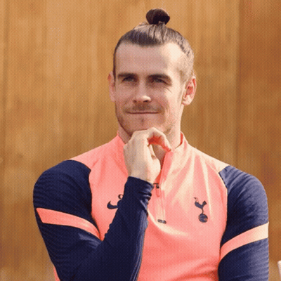 A Man With A Bun On His Head Is Wearing A Pink Shirt With The Letters Tottenham On It GIF