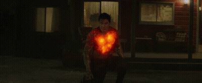 A Man With A Burning Heart On His Chest Stands In Front Of A House GIF