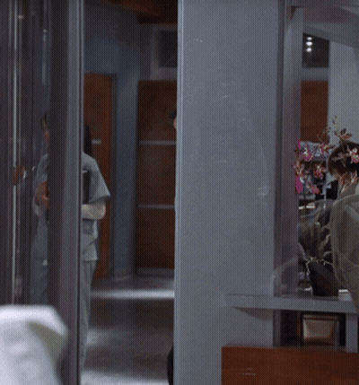 A Man With A Cane Is Standing In A Hallway Next To A Woman GIF