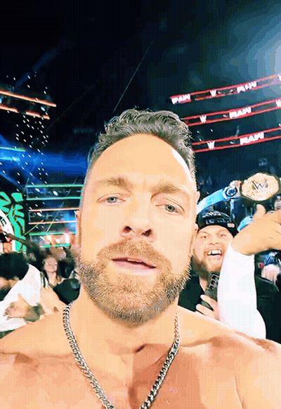 A Man With A Chain Around His Neck Holds Up A Wrestling Championship Belt GIF