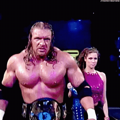 A Man With A Championship Belt Is Walking With A Woman In A Pink Top Behind Him . GIF