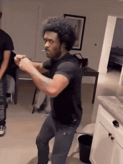 A Man With A Cigarette In His Mouth Is Dancing In A Living Room GIF