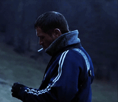 A Man With A Cigarette In His Mouth Wearing A Blue Adidas Jacket GIF