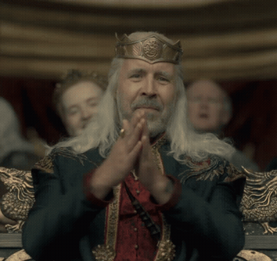 A Man With A Crown On His Head Is Clapping His Hands Together GIF