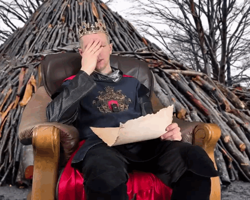 A Man With A Crown On His Head Is Sitting In A Chair GIF