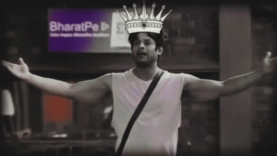 A Man With A Crown On His Head Stands In Front Of A Sign That Says Bharatpe GIF