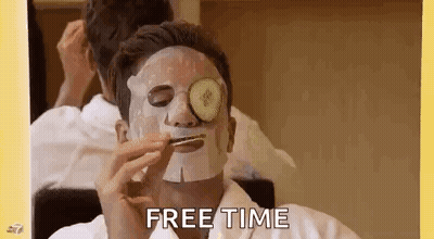 A Man With A Face Mask And Cucumber Slices On His Eyes Is Eating A Sandwich . GIF