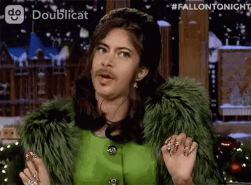 A Man With A Fake Beard And Mustache Is Wearing A Green Fur Coat And A Green Dress . GIF