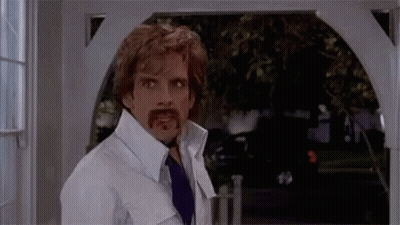 A Man With A Fake Mustache Is Standing In Front Of A Doorway . GIF