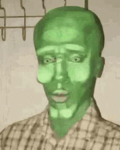 A Man With A Green Face Is Wearing A Plaid Shirt And Has A Green Mask On His Face . GIF