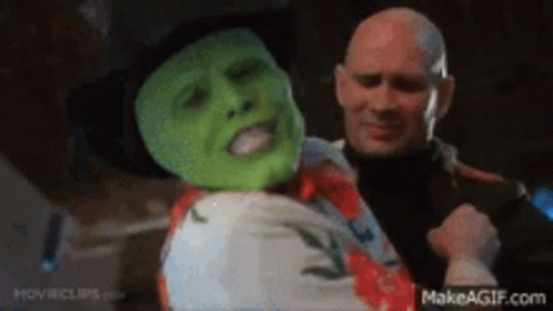 A Man With A Green Mask Is Being Held By Another Man GIF
