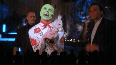 A Man With A Green Mask Is Holding A Rabbit In Front Of A Crowd GIF